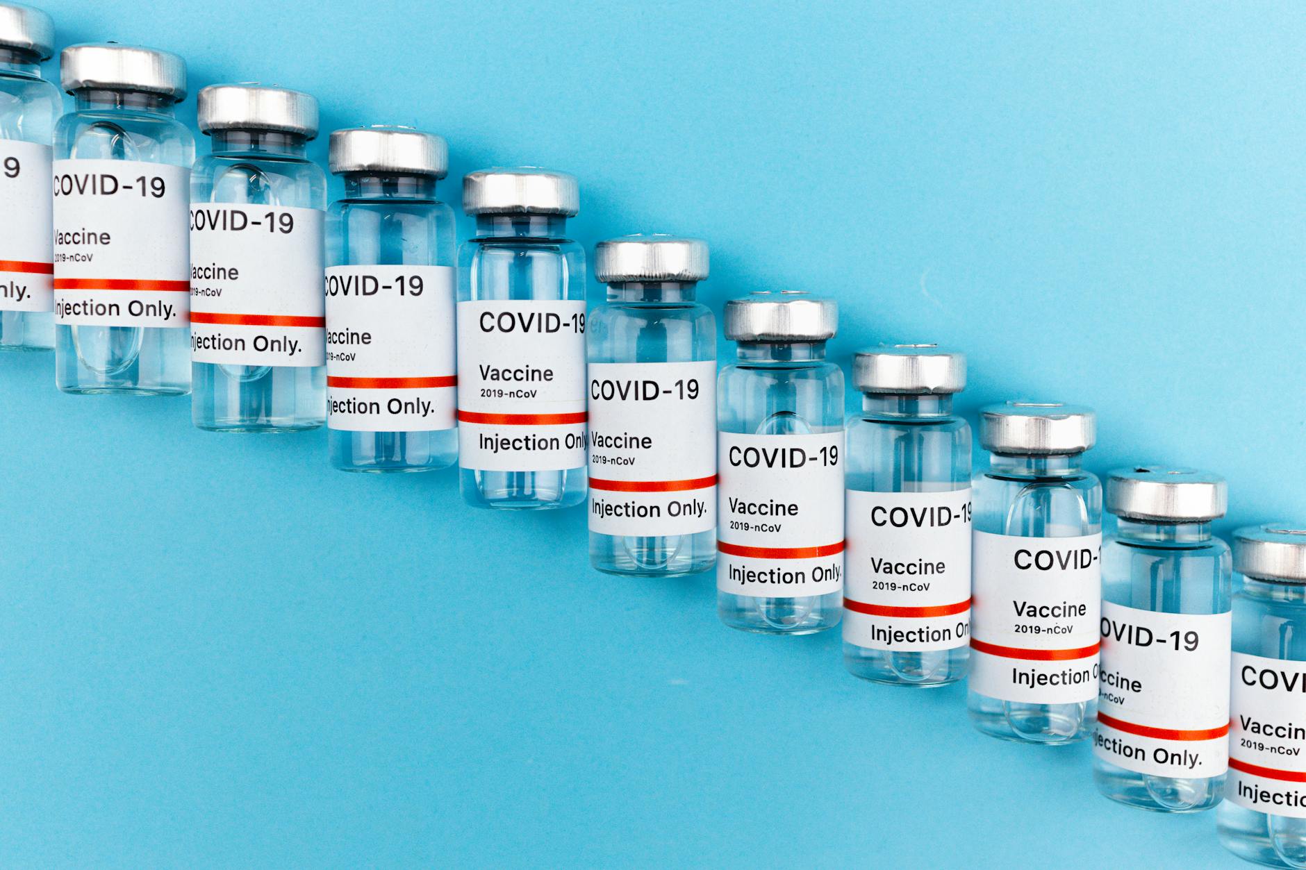 Close-up of multiple COVID-19 vaccine vials lined up on a blue surface.
